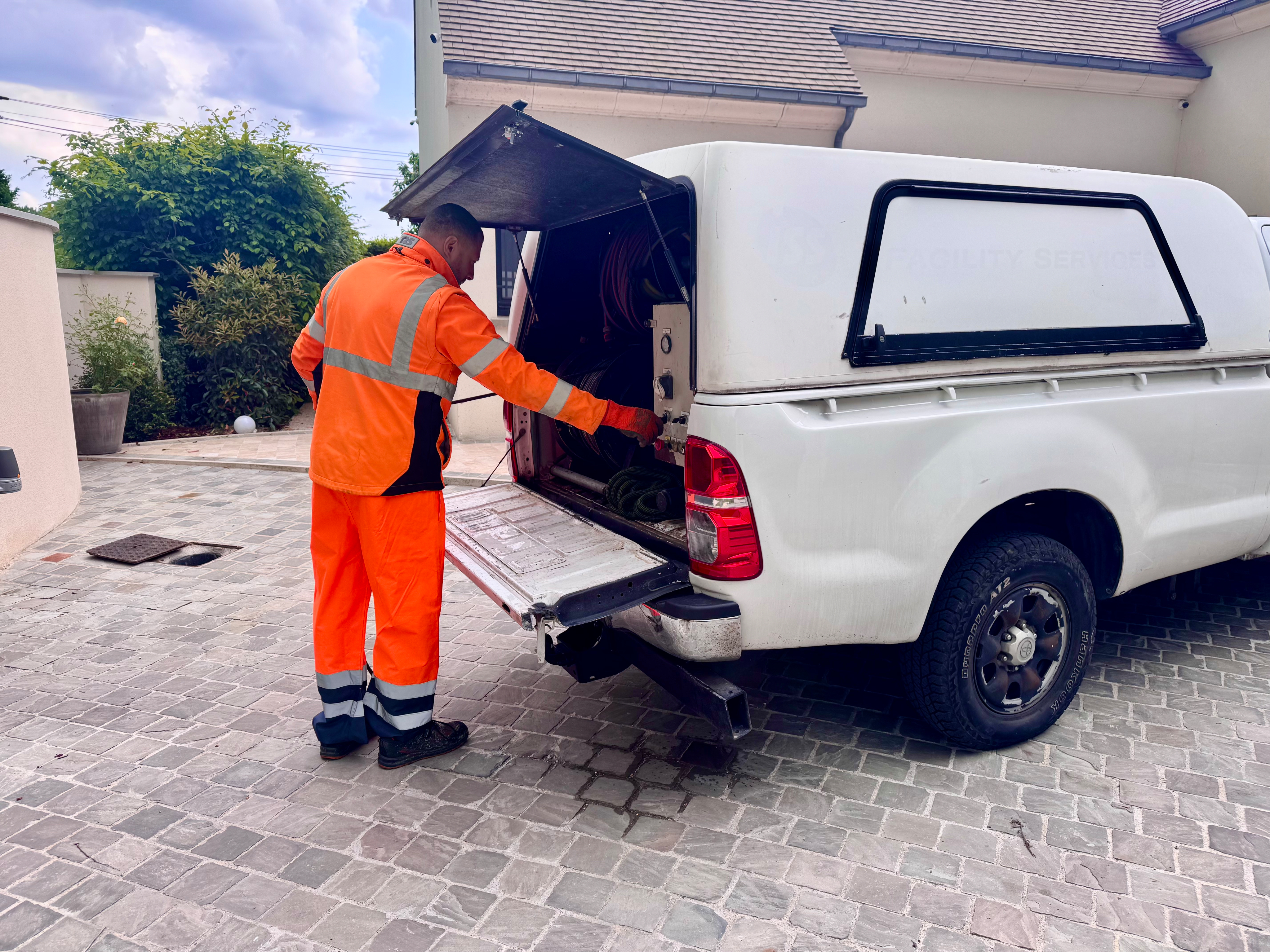 Photo d'un technicien En pleine intervention à l'arrière de son véhicule d'hydro-curage.
